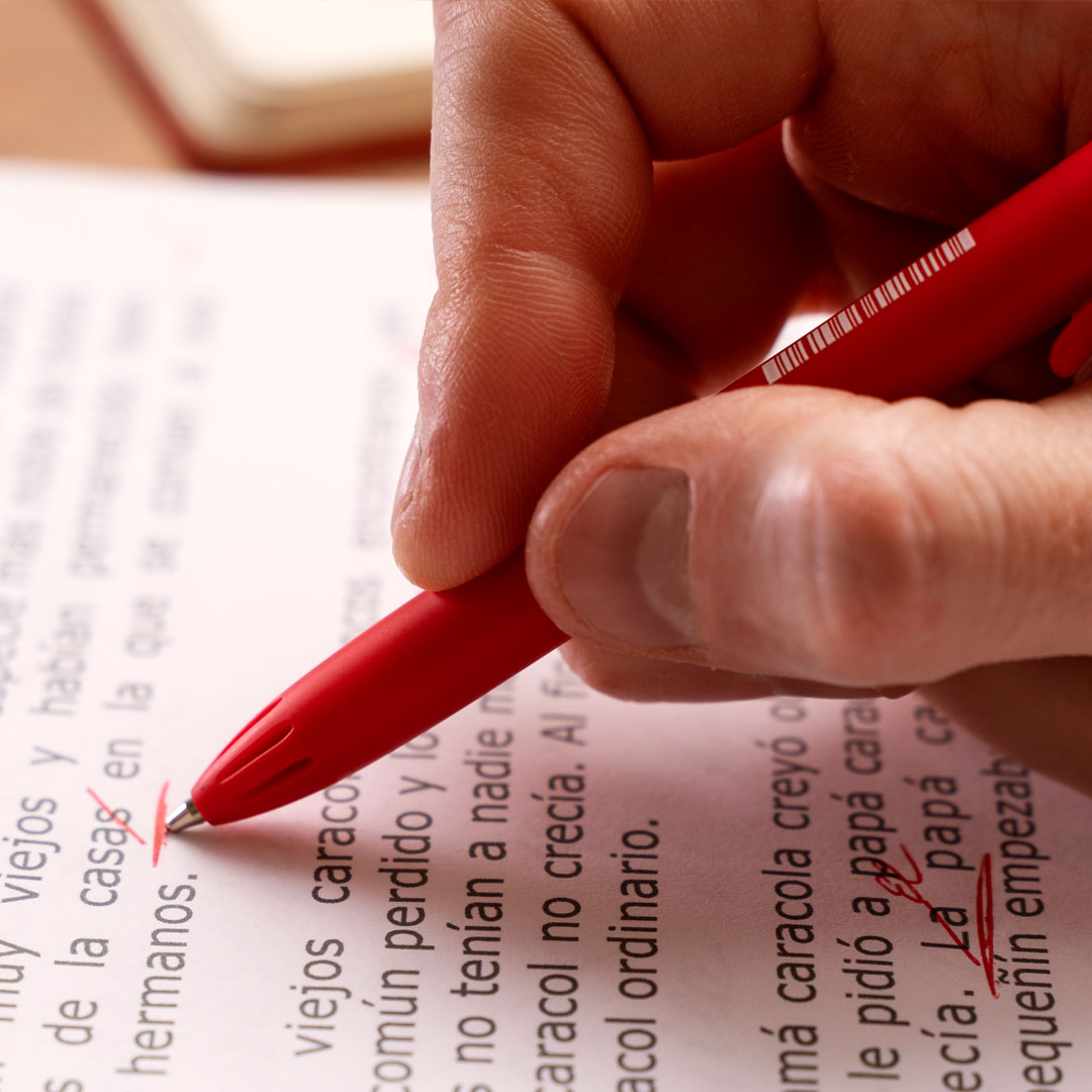 Editor professionista rivede un manoscritto cartaceo con penna rossa